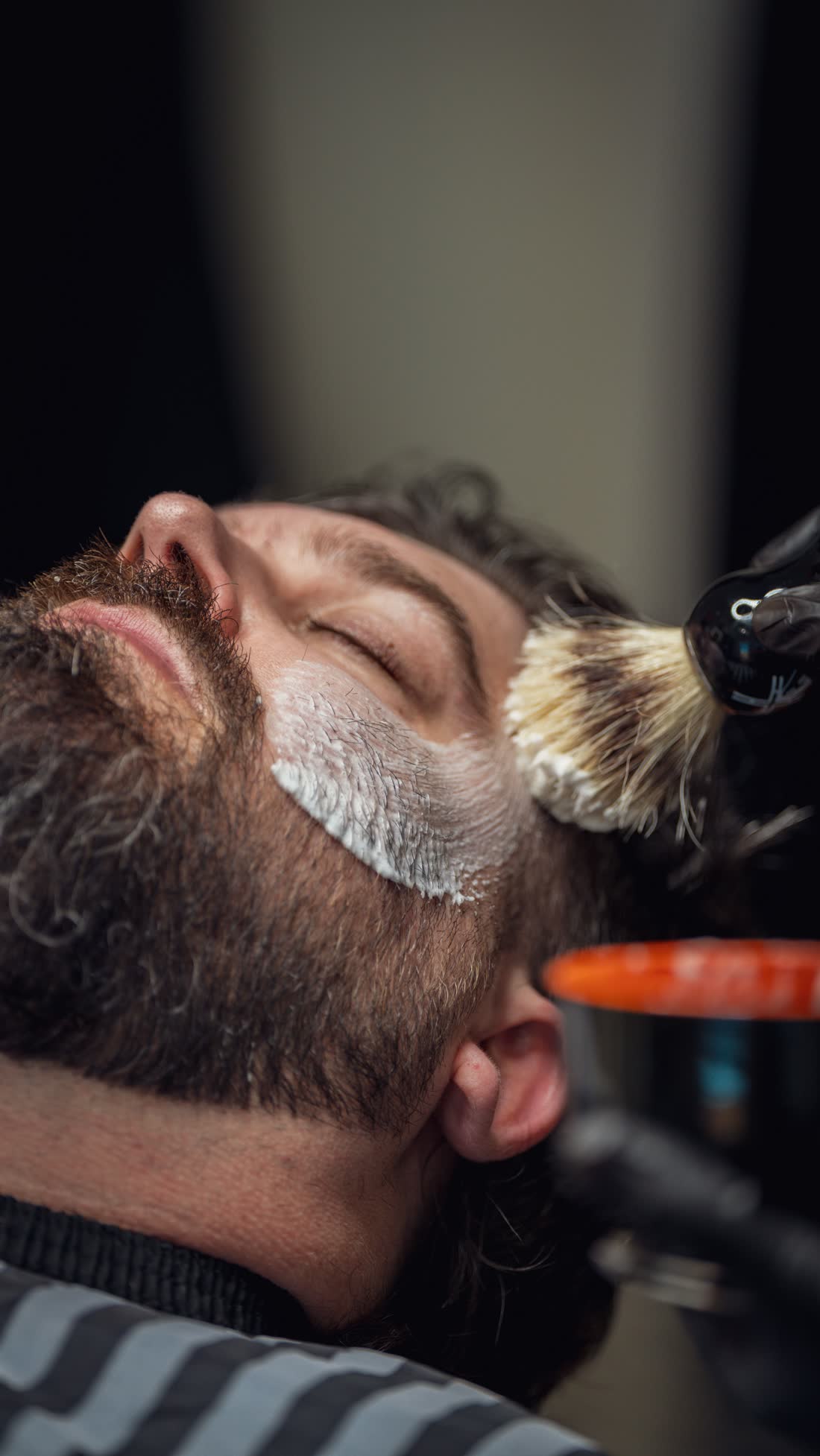 Cliente com espuma de barbear sendo aplicada com pincel